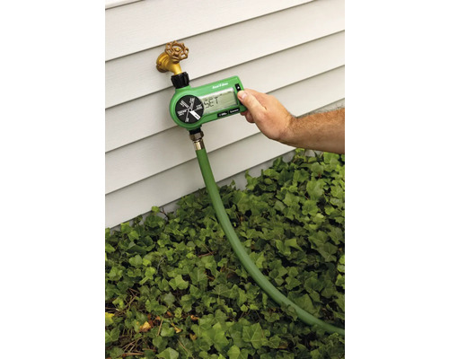 Ordinateur d''arrosage de jardin raccordé à un robinet avec un tuyau, l''arrosage est réglé par une personne.