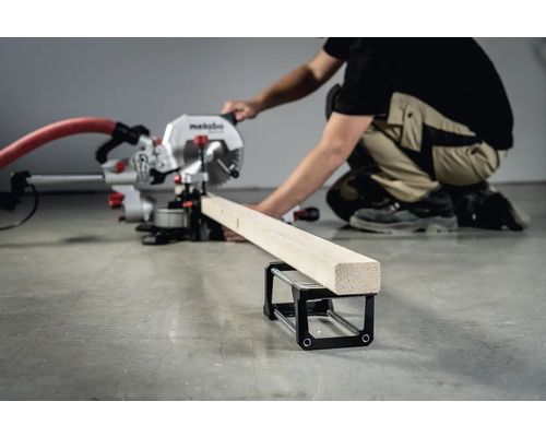 Scie à onglet Metabo coupant une pièce de bois avec une personne en arrière-plan