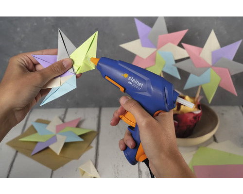 Un pistolet à colle chaude est utilisé pour fixer une étoile en papier.