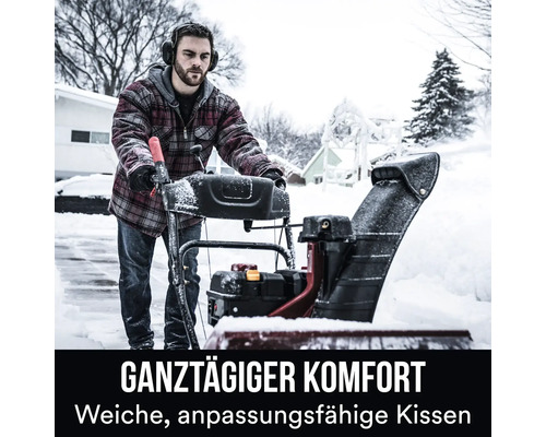 Une personne utilise une fraise à neige sur une allée enneigée.