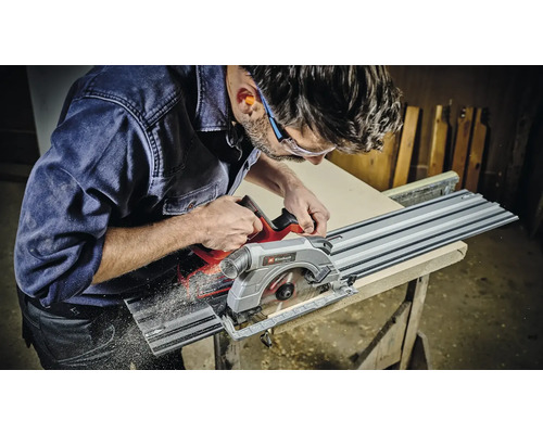 Ein Mann schneidet ein Holzbrett mit einer Tauchsäge und Führungsschiene von Einhell.