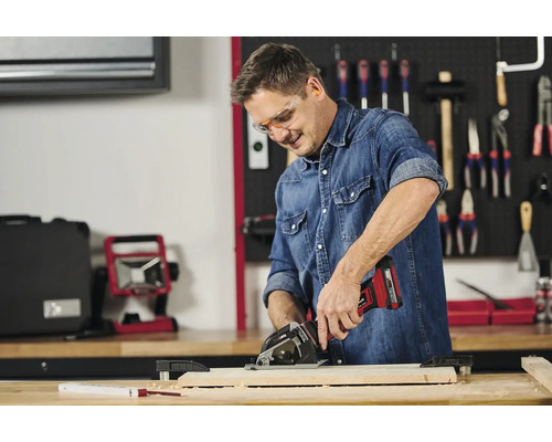 Mann arbeitet mit einer Akku-Handkreissäge an einem Holzstück