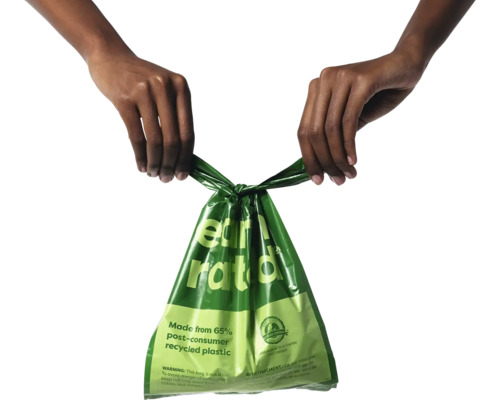 Un sac poubelle vert, tenu par deux mains, fabriqué à partir de plastique recyclé.