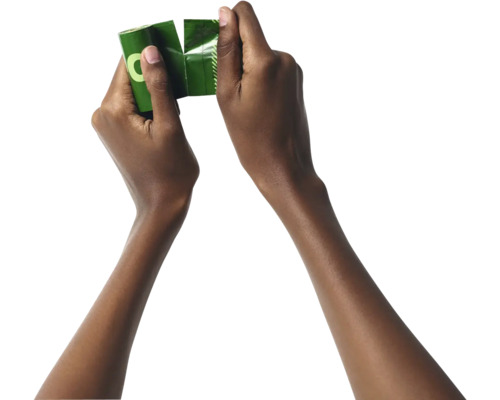 Deux mains déchirent un emballage pour sacs à déjections canines