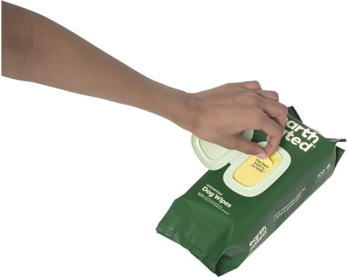 Une main tire une lingette d''un paquet de lingettes pour chiens.