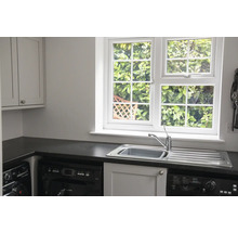 Heller Waschraum mit Spüle, Fenster und Waschmaschine.