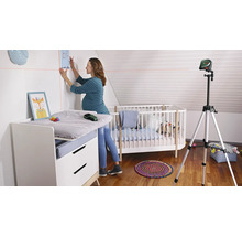 Une femme fixe une photo au mur d''une chambre d''enfant à l''aide d''un laser à lignes.
