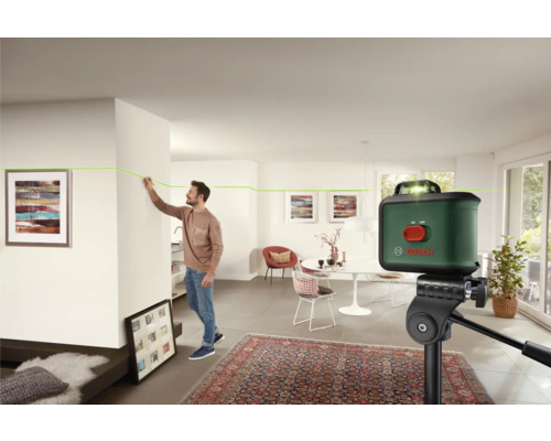 Raumszene mit einem Mann, der mit einem Laser-Nivelliergerät eine Linie an einer Wand markiert, Bosch Logo