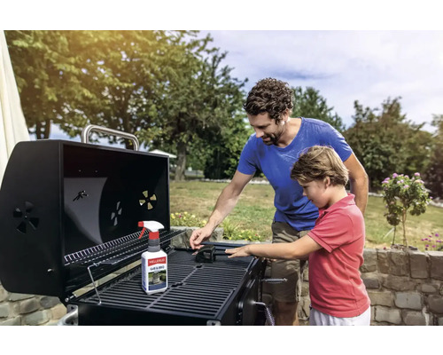 Vater und Sohn reinigen einen Grill mit Grillreiniger und Bürste im Freien.