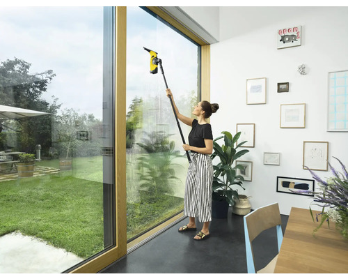 Femme nettoie les fenêtres avec un aspirateur de fenêtre à l''intérieur.