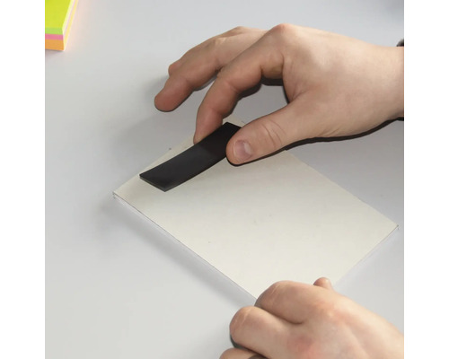 Hand mit Magnetstreifen auf weißem Karton