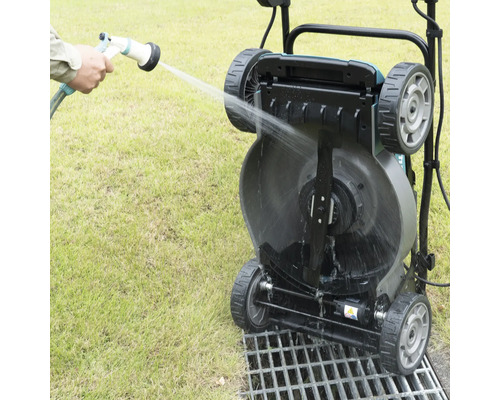 Un rouleau à gazon est nettoyé avec un tuyau d''arrosage.