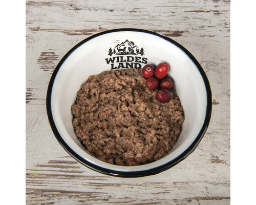 Hundenassfutter in einem Napf mit Preiselbeeren und Wildes Land Logo