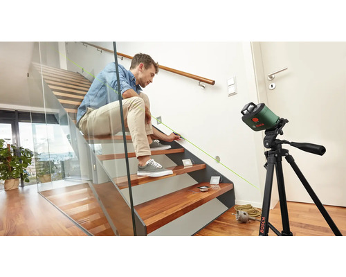 Un homme utilise un laser linéaire sur un escalier pour faire des marquages.