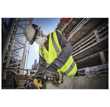 Un ouvrier du bâtiment utilise une meuleuse d''angle sur un chantier, portant des vêtements de protection.