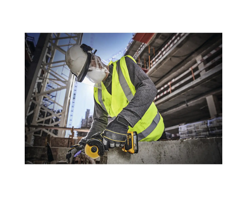 Un ouvrier du bâtiment utilise une meuleuse d''angle sur un chantier, portant des vêtements de protection.