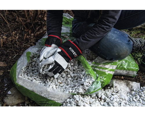 Person befüllt Sack mit Zierkies mit Gartenhandschuhen