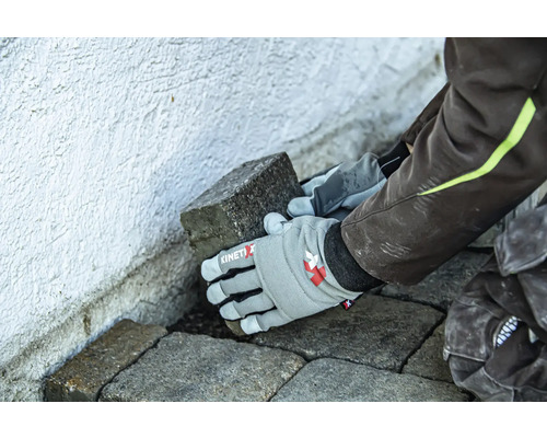 Eine Person verlegt Pflastersteine mit Arbeitshandschuhen.