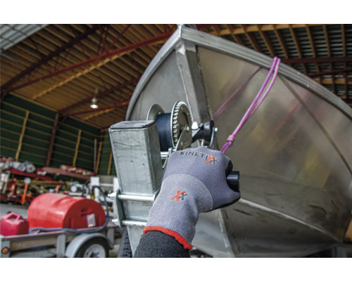 Eine Person mit Arbeitshandschuhen bedient eine Bootswinde an einem Bootsanhänger.