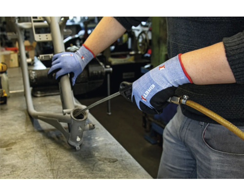 Ein Mann reinigt ein Fahrradrahmenlager mit einem Werkzeug und trägt dabei Arbeitshandschuhe