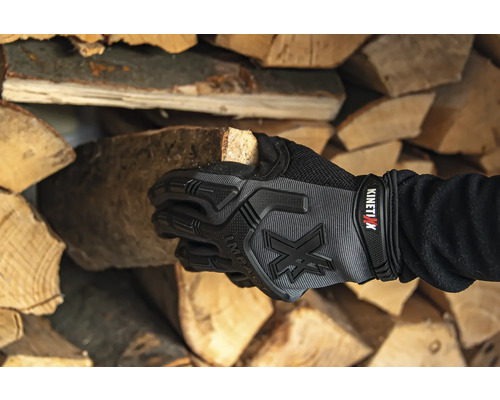 Main avec gant de travail tenant une bûche de bois devant une pile de bois