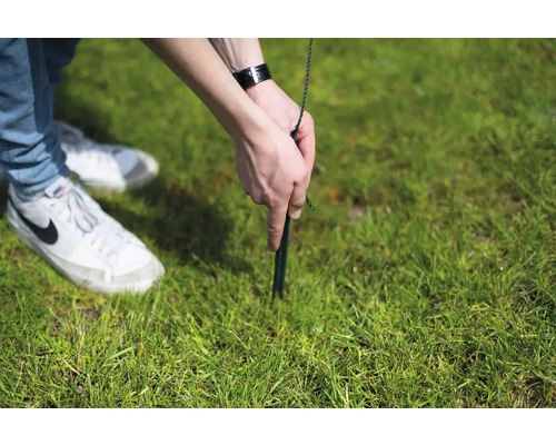 Une personne fixe un piquet dans l''herbe