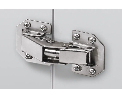 Charnière métallique fixée à une porte de meuble avec des vis