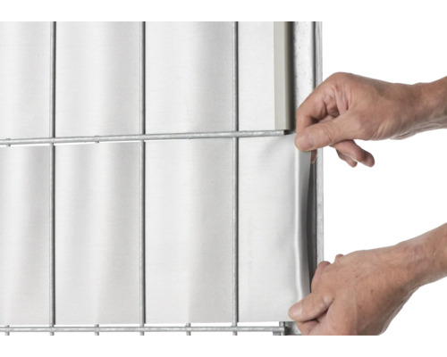 Person befestigt Sichtschutzstreifen an einem Doppelstabmattenzaun.