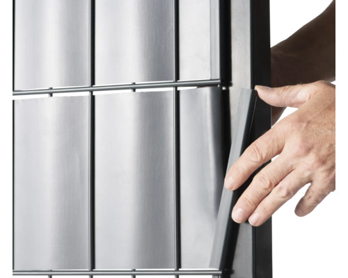 Detailaufnahme einer Person, die einen Sichtschutzstreifen in einen Zaun einfädelt.