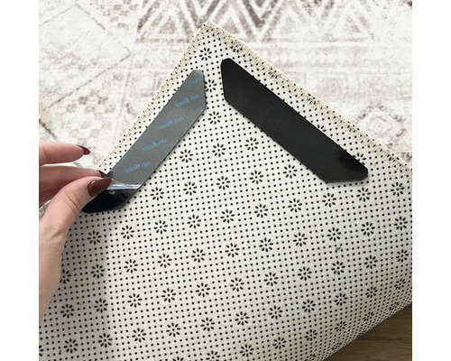 Deux dispositifs antidérapants pour tapis sur un tapis pour la fixation et le maintien.