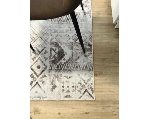 Tapis à motifs graphiques sous une chaise sur un plancher en bois.