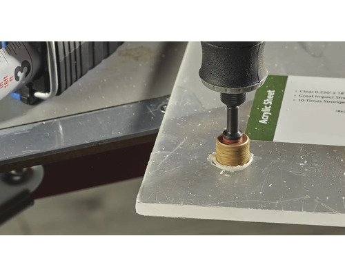 Eine Bohrmaschine bohrt ein Loch in eine Acrylglasplatte.