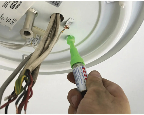 Un homme répare un plafonnier avec un stylo de retouche.