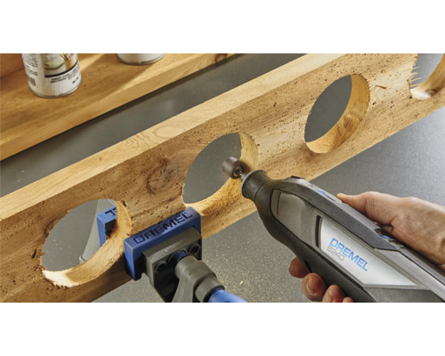 Outil multifonction Dremel travaillant une pièce de bois avec des évidements ronds, fixée avec un serre-joint