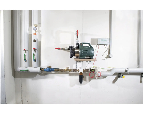 Hauswasserwerk-Installation mit Pumpe, Rohren und zugehöriger Technik an einer Wand