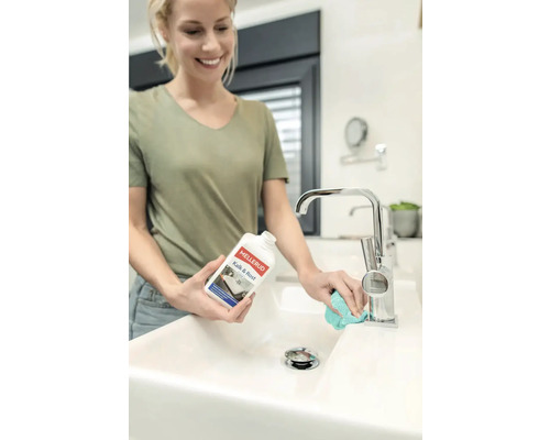 Femme nettoie lavabo avec un produit anti-calcaire et antirouille