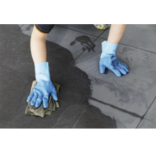 Personne nettoyant un sol carrelé avec un chiffon et des gants