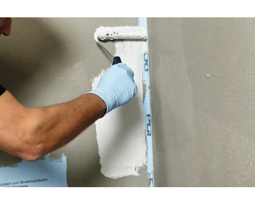 Une personne applique un produit d''étanchéité sur un mur à l''aide d''un rouleau à peinture.