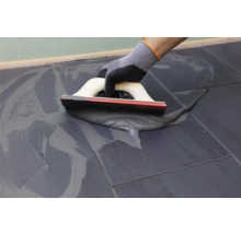 Carreleur utilisant une spatule pour jointoyer des carreaux