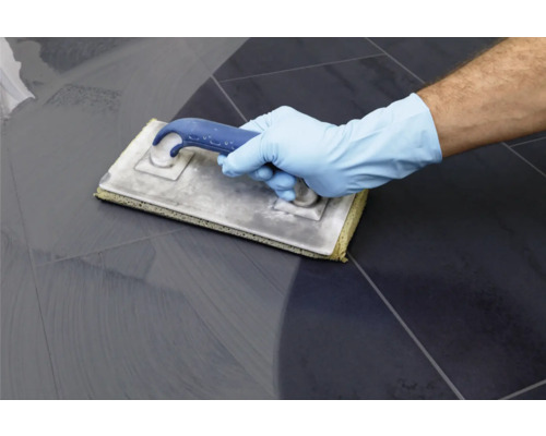 Carreleur appliquant du coulis sur des carreaux de sol avec une taloche à joints