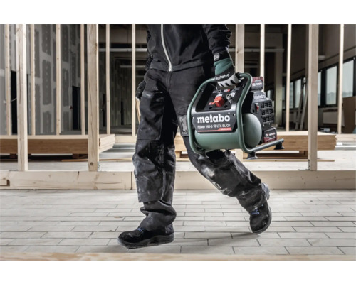 Une personne transporte un compresseur Metabo Power 160-5 18 LTX BL OF sur un chantier.