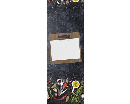 Holzschneidebrett mit Rezeptpapier umgeben von Kräutern und Gewürzen