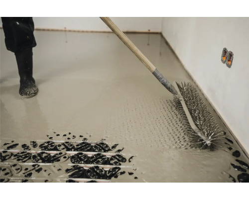 Estricharbeiten mit einer Stachelwalze auf einer Fußbodenheizung.