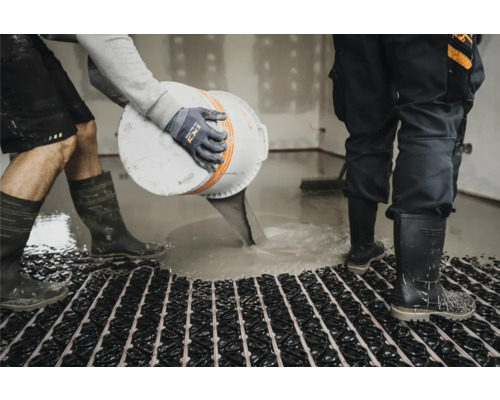 Handwerker gießt Estrich auf eine Fußbodenheizung im Innenbereich.