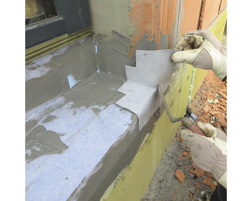 Handwerker bei der Fensterabdichtung mit Dichtungsband und Spachtel.