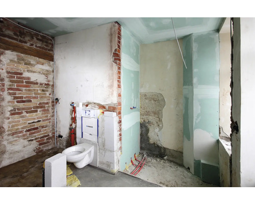 Badezimmerbaustelle mit Ziegelwand, Toilette und Trockenbau