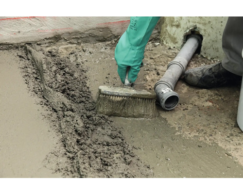 Handwerker mit Bürste beim Verfugen eines Bodens mit Fugenmasse.