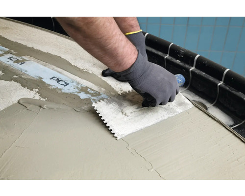Carreleur appliquant de la colle sur un support avec une spatule crantée