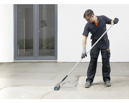 Handwerker trägt mit einer Farbwalze eine Beschichtung auf einen Betonboden auf.