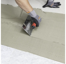 Carreleur appliquant de la colle à carrelage sur une surface à l''aide d''une truelle